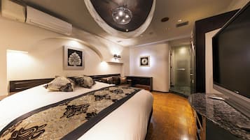 Una habitación de hotel moderna con una cama grande, un televisor de pantalla plana y una encimera de mármol.