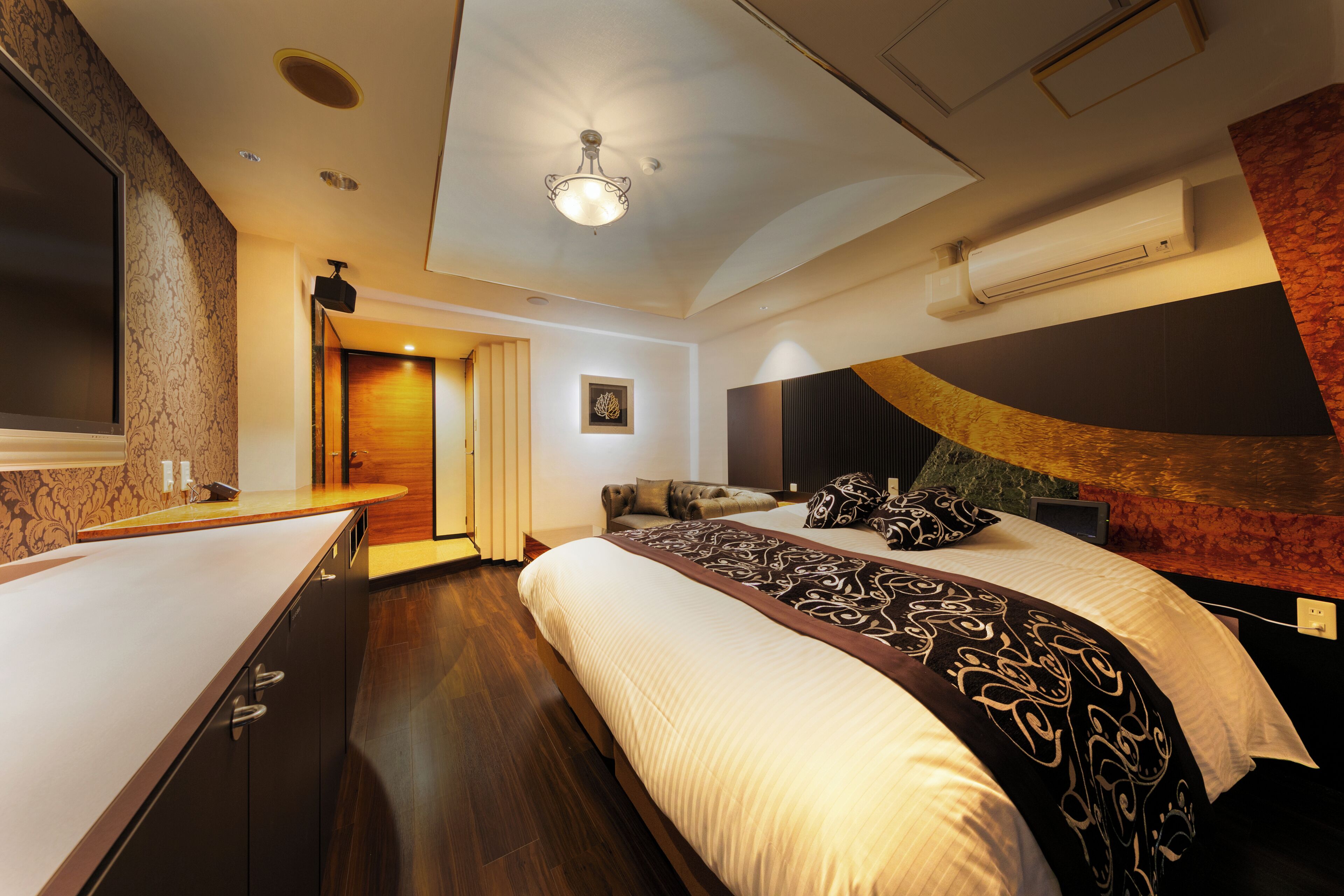 Una habitación de hotel moderna con una cama grande, un escritorio y una lámpara en el techo.