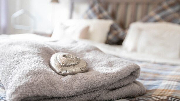 A neatly made bed with a folded towel and a heart-shaped object on it. - Apartment 'Ferienwohnung Stielbruch' with Private Terrace, Private Garden and Wi-Fi (Viöl)