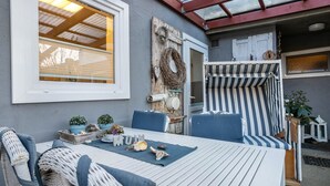 A patio with a table, chairs, and a striped sofa. - Apartment 'Ferienwohnung Stielbruch' with Private Terrace, Private Garden and Wi-Fi (Viöl)