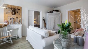 A room with a white sofa, a white rocking chair, a white cabinet, and a wall-mounted deer head. - Apartment 'Ferienwohnung Stielbruch' with Private Terrace, Private Garden and Wi-Fi (Viöl)