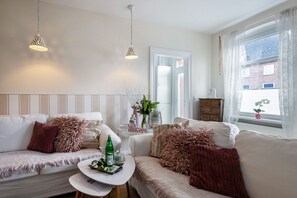 A modern living room with a sofa, a small table, and a window with curtains.