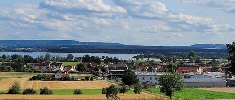 A rural landscape with fields, a village, and a lake.