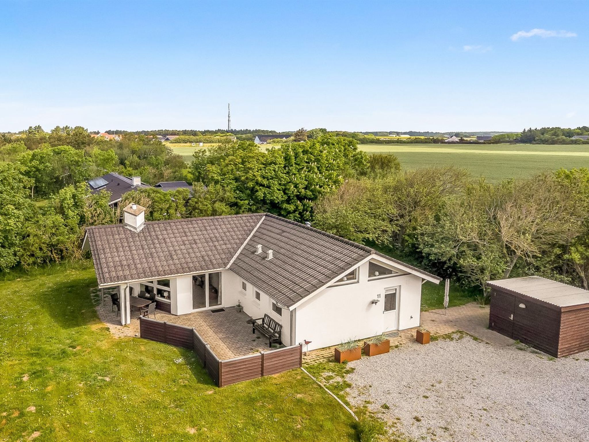 Een gelijkvloers huis met een schuin dak, een overdekte patio en een oprit met grind.