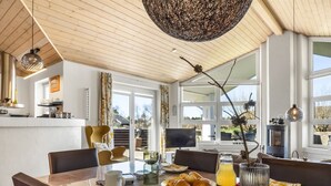 A modern dining area with a wooden table, chairs, and a large window offering a view of the outdoors. - "Ljuba" - 1.3km from the sea by Interhome (Hjørring)