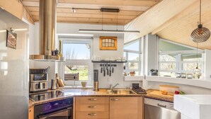 A modern kitchen with wooden cabinets, stainless steel appliances, and large windows. - "Ljuba" - 1.3km from the sea by Interhome (Hjørring)
