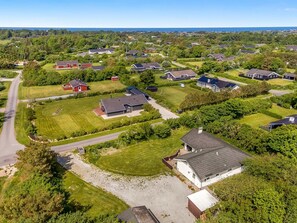 Vue aérienne d’un quartier résidentiel avec des maisons, des routes et de la végétation.