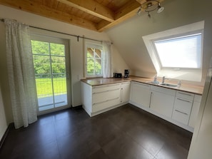 Una cucina moderna con un'ampia finestra, un balcone e un soffitto in legno.