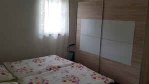 A bedroom with a bed, a wardrobe, and a window with curtains. - Apartment 'Ferienwohnung 2' with Private Terrace and Wi-Fi (Sulzbach an der Murr)