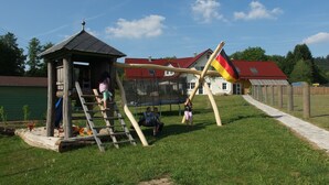 A playground with a wooden structure, a trampoline, and a flagpole with a flag. - Apartment 'Ferienwohnung 2' with Private Terrace and Wi-Fi (Sulzbach an der Murr)
