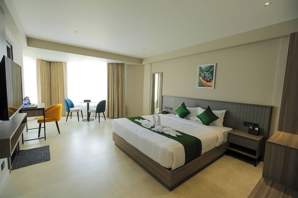 A hotel room with a large bed, a desk, a chair, and a television.