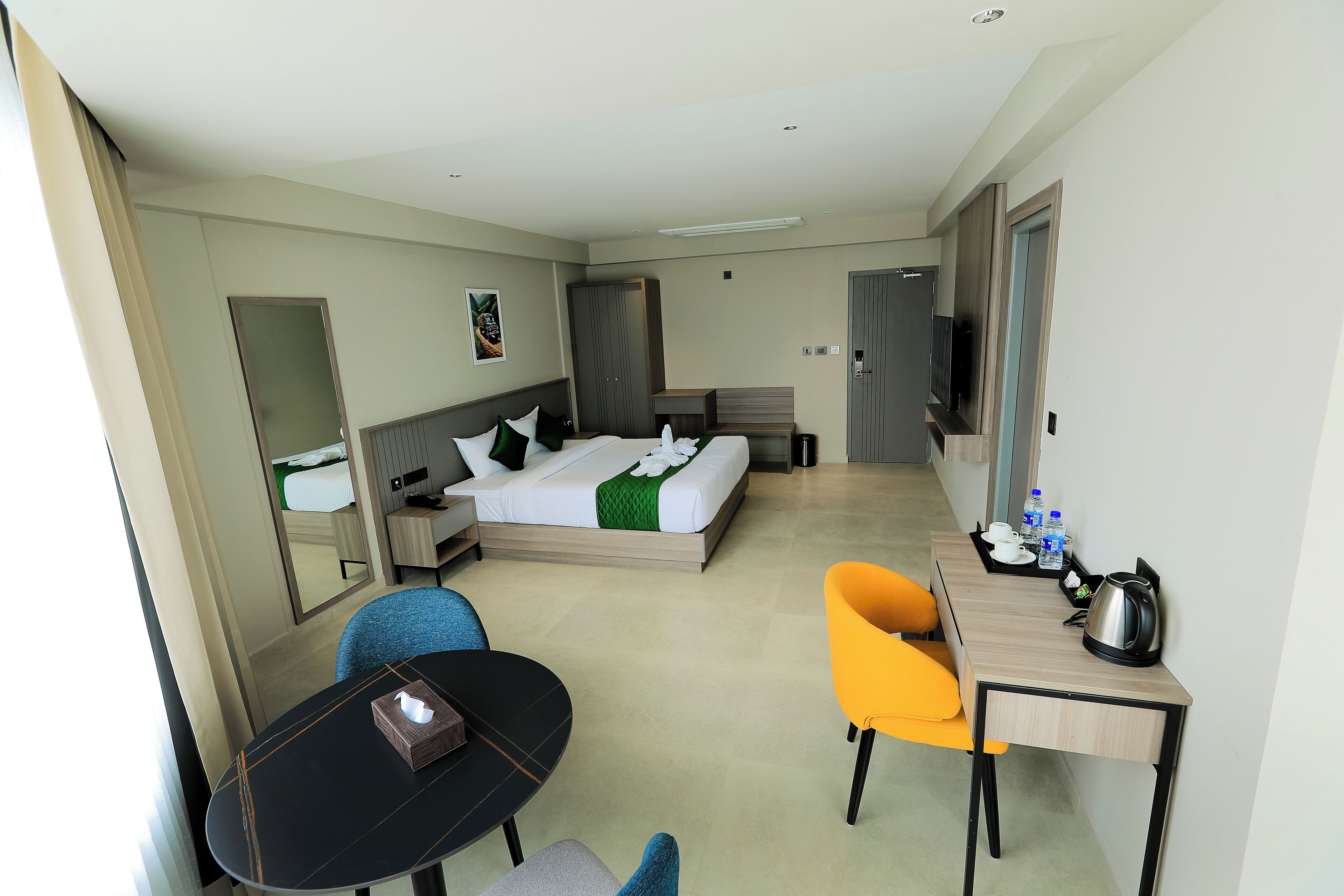 Une chambre d’hôtel moderne équipée d’un lit, d’un bureau avec une bouilloire, d’une chaise et d’une petite table.