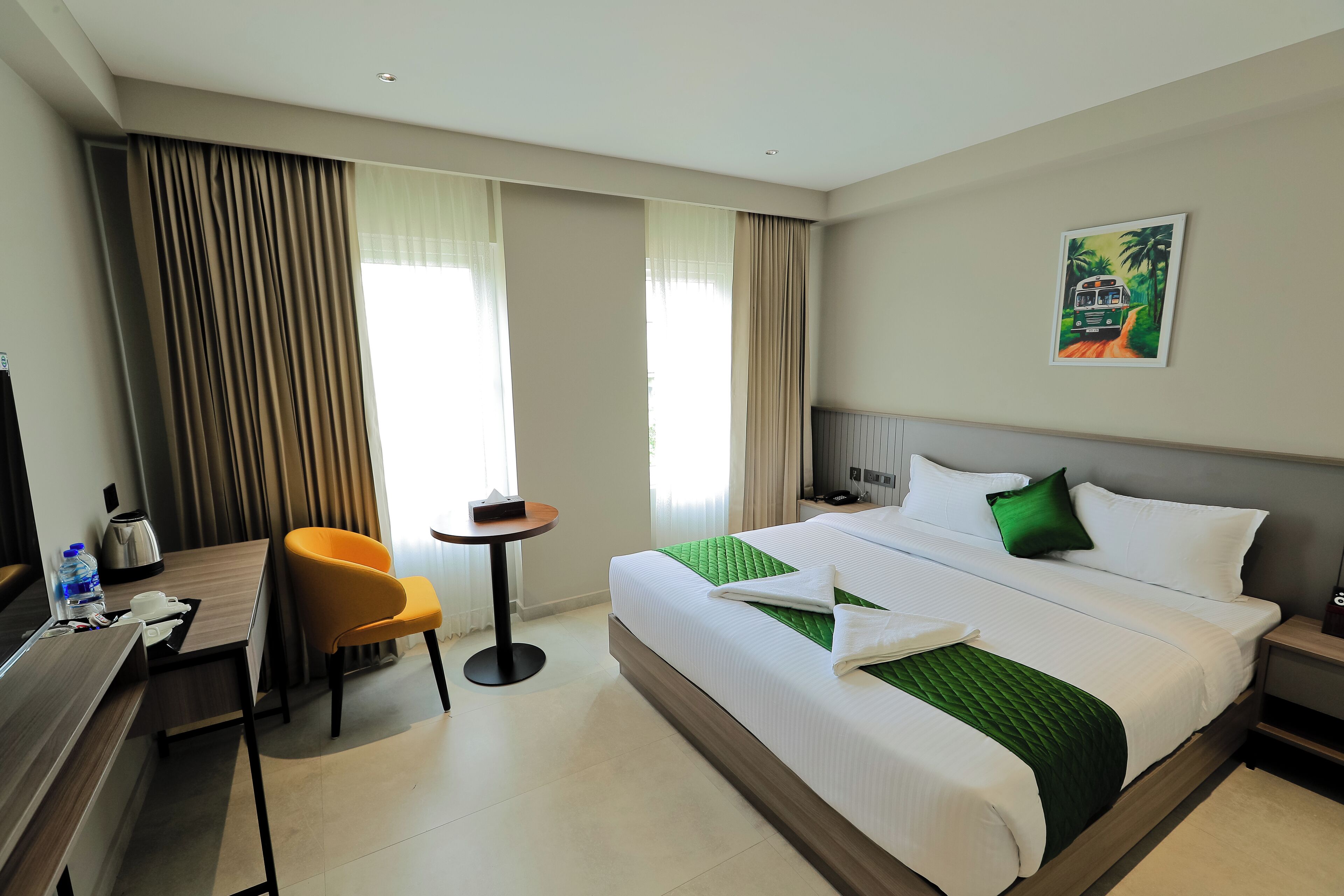 A hotel room with a large bed, a desk, a chair, a small table, and a painting on the wall.