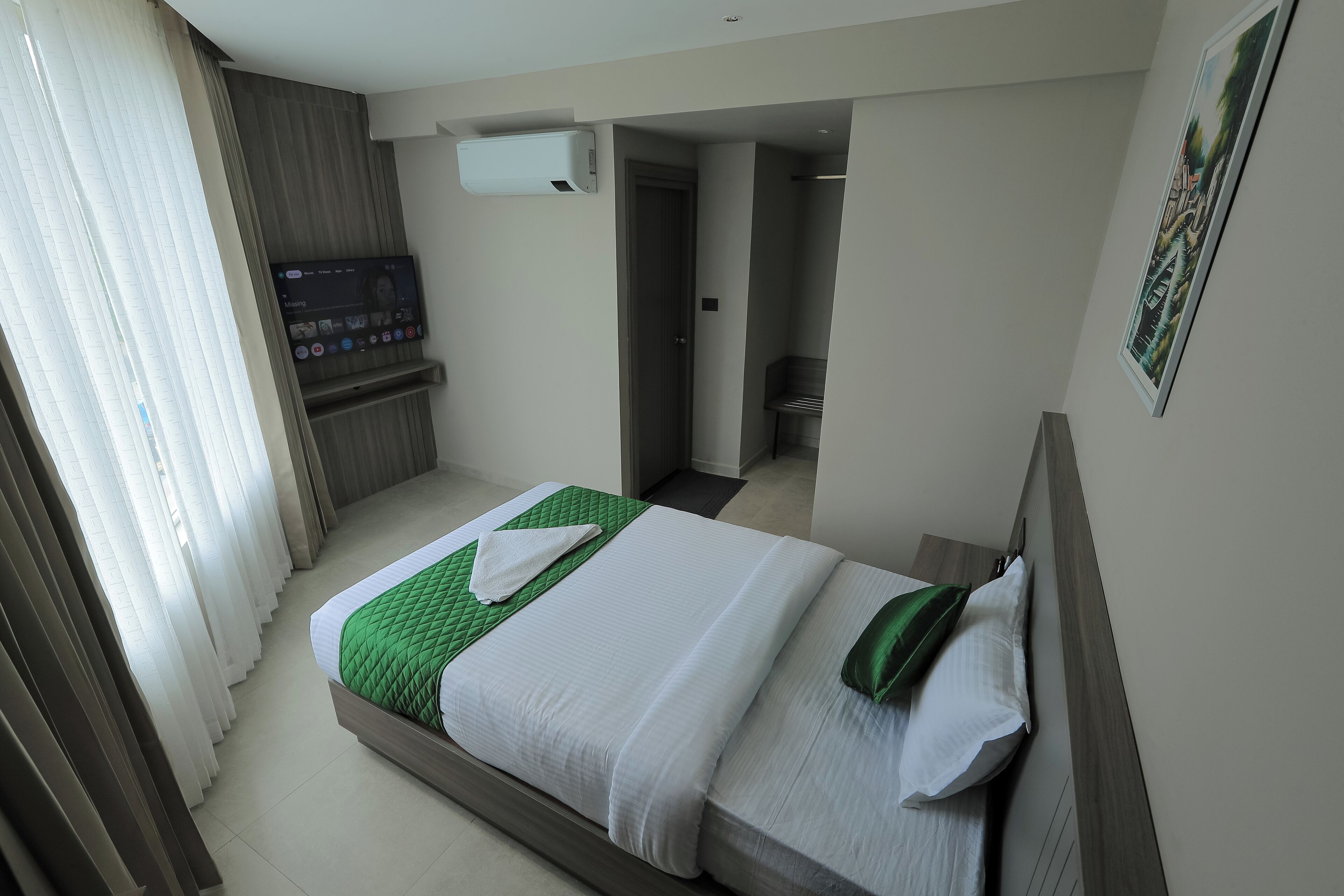 A hotel room with a bed, a TV, and a bathroom.