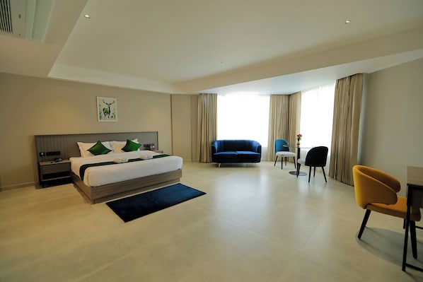 Ein modernes Hotelzimmer mit einem großen Bett, einer Couch, einem Schreibtisch und einem Stuhl.