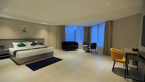 A modern hotel room with a large bed, a sofa, a desk, and a chair. - Mount Land (Sulthan Bathery)