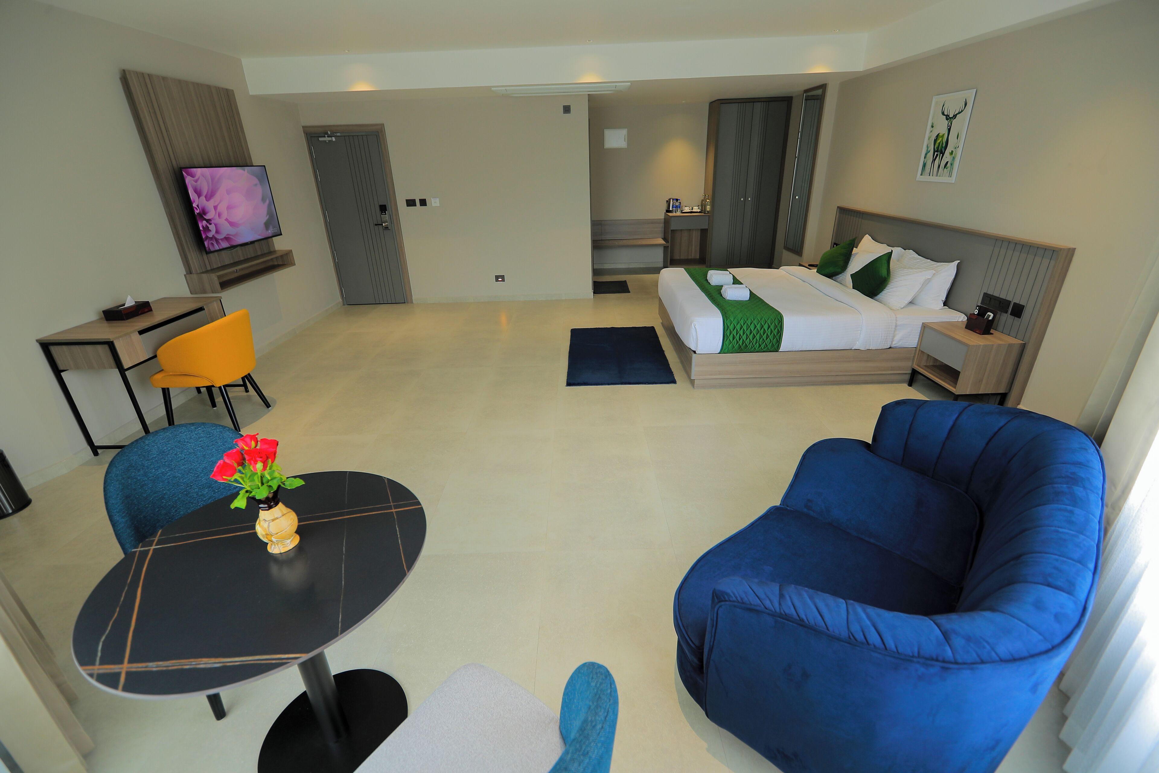 A modern hotel room with a bed, a desk, a chair, and a sofa.