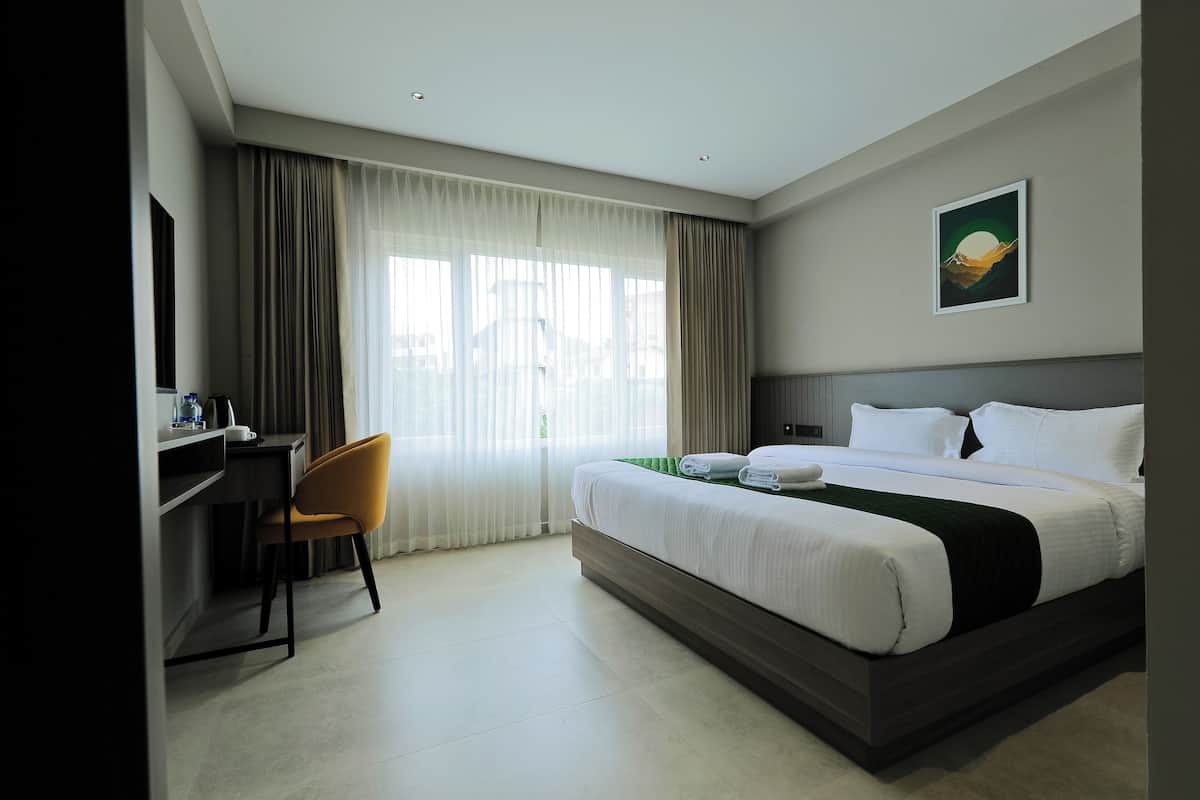 A hotel room with a bed, a desk, and a chair.