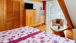 A bedroom with a bed, a TV, a wardrobe, a chair, and a small table.