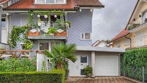 A two-story house with a balcony, a garage, and a well-maintained garden.