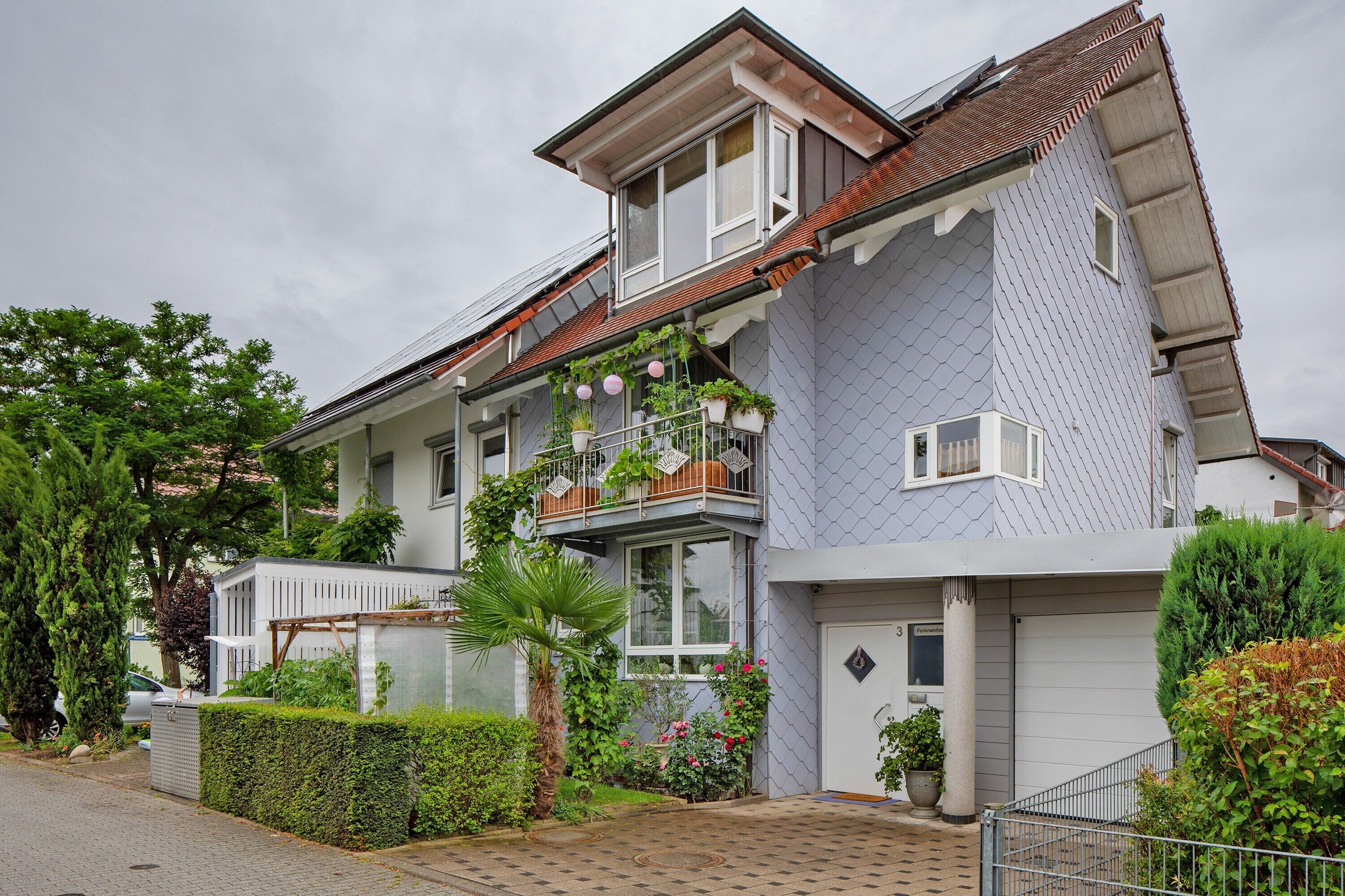 Ein zweistöckiges Wohnhaus mit Balkon, Garage und einem gepflegten Garten.