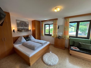 A bedroom with a bed, a sofa, a small round rug, a painting, and a window with curtains. - Apartment 'Frauenmantel Mit Extra Doppelzimmer' with Mountain View, Shared Pool and Wi-Fi (St. Johann im Pongau)