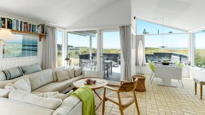 Ein geräumiges Wohnzimmer mit einer großen Couch, einem Esstisch und Blick ins Freie.