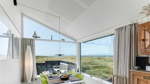 Ein Essbereich mit Tisch, Stühlen und Blick auf den Strand.
