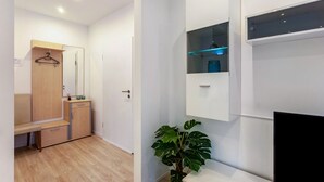 Una habitación moderna con un banco de madera, un armario, un espejo, una planta y estanterías empotradas.
