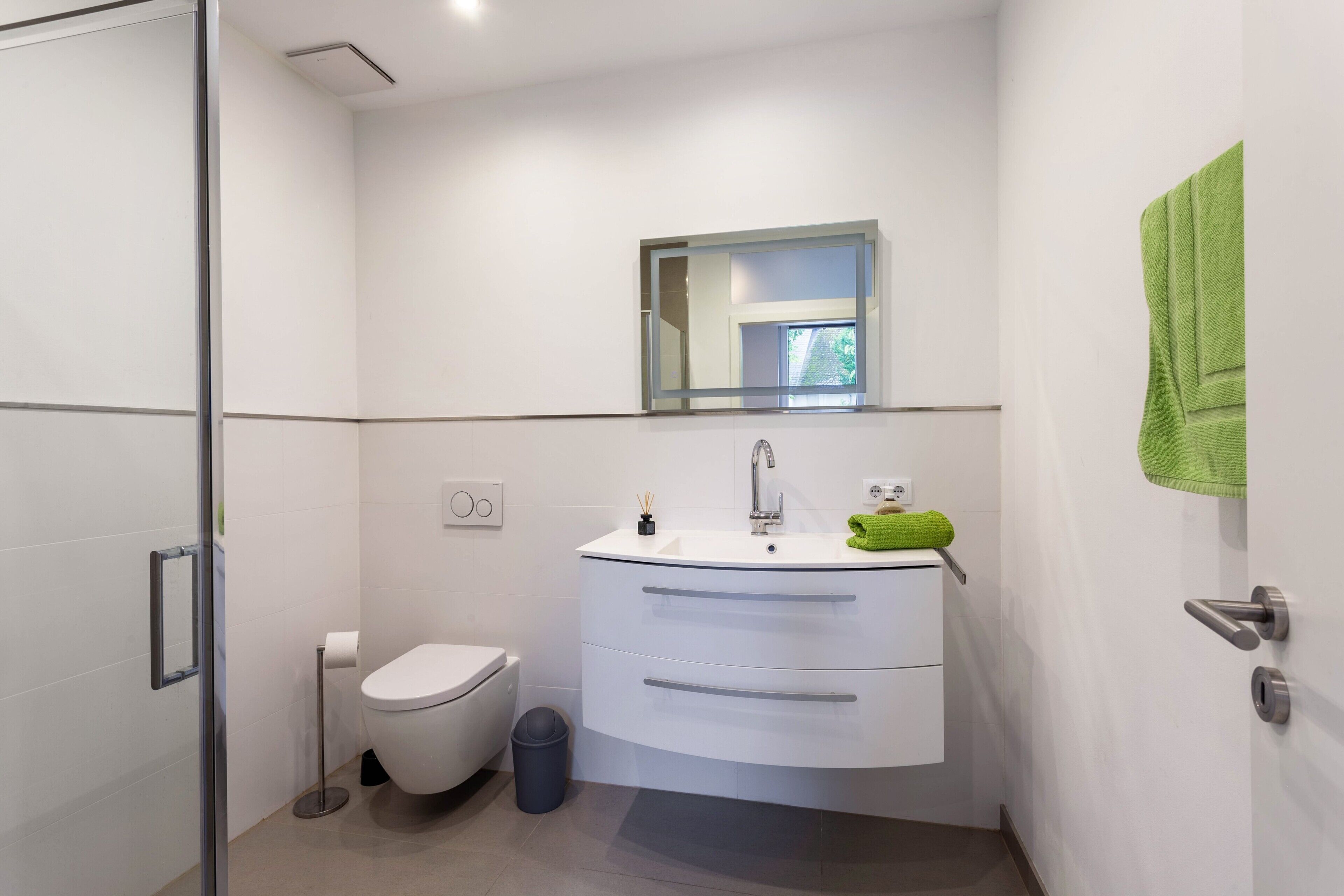 Ein modernes Badezimmer mit Toilette, Waschbecken und Spiegel.