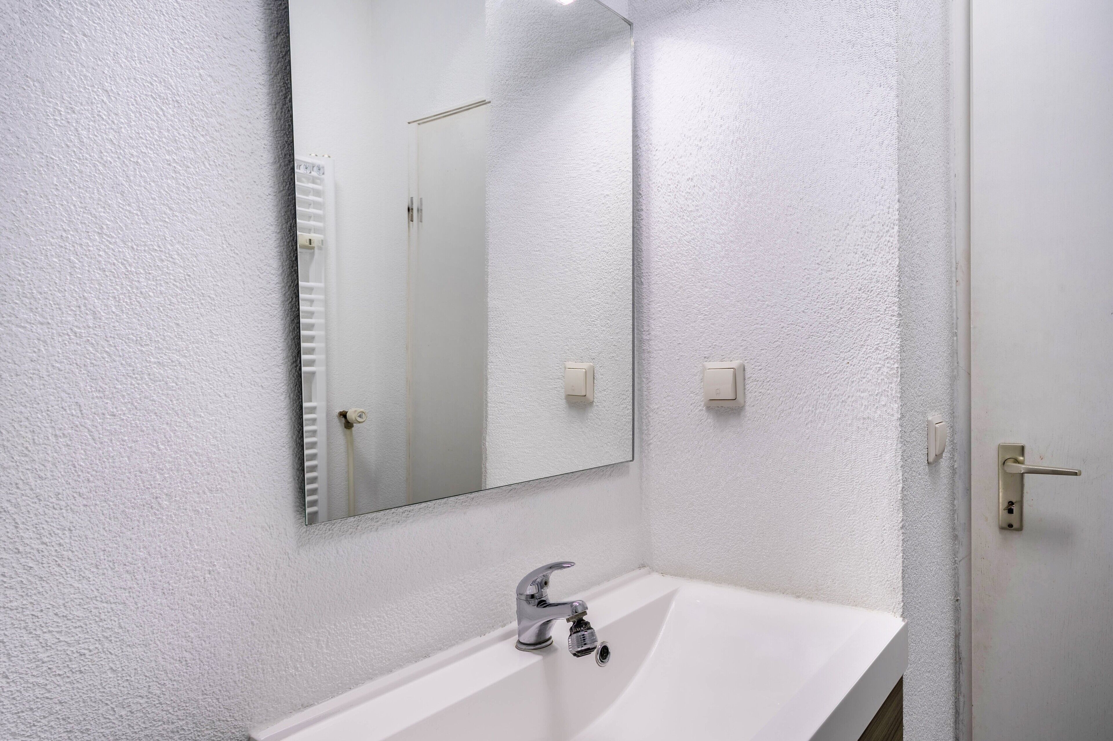 A bathroom with a white sink, a mirror, and a door.