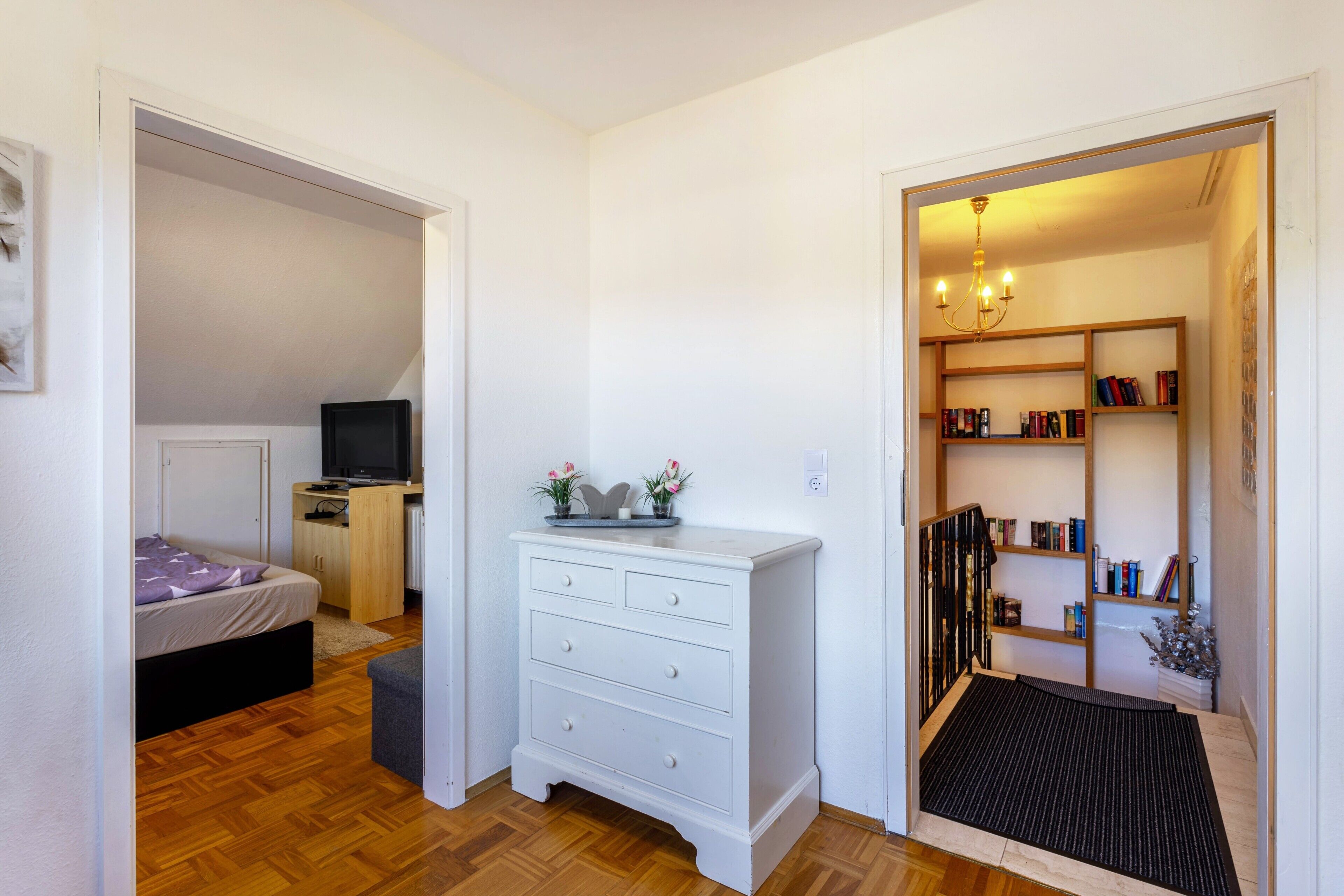 A bedroom with a bed, a desk, a dresser, and a bookshelf.