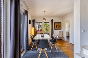 A dining area with a table and chairs, a view through a glass door, and a staircase leading to another room.