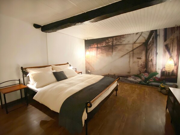 Une chambre avec un lit en bois, une table de chevet, une chaise et une fresque murale.