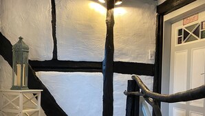 A wooden staircase with a black and white painted wall, a white door labeled 'Privat,' and a small white table with a lantern. - Apartment 'Haus Auenland' with Shared Terrace, Garden, and Wi-Fi (Feldatal)