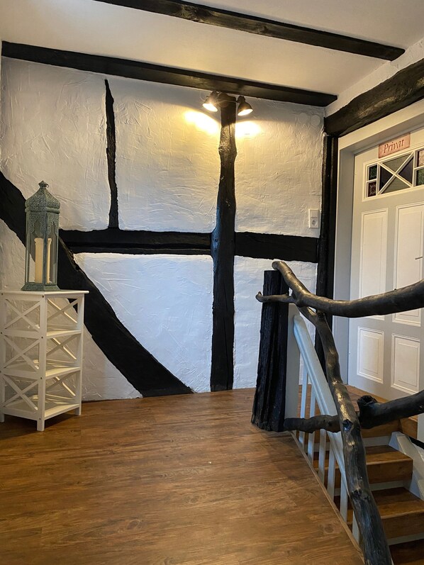 Eine hölzerne Treppe mit einer schwarz-weiß gestrichenen Wand, einer weißen Tür mit der Aufschrift 'Privat' und einem kleinen weißen Tisch mit einer Laterne.