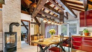 A modern kitchen with a central island, wooden beams, and a stone wall. - Apartment 'Wohnung Am Stadtrand Im Grünen' with Private Terrace, Private Garden and Wi-Fi (Zeuthen)