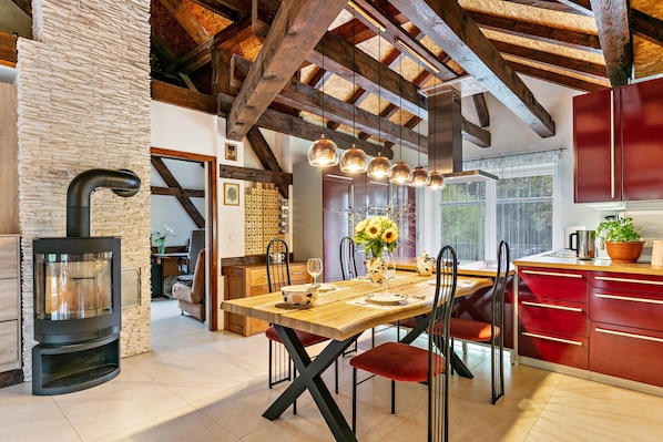 A modern kitchen with a central island, wooden beams, and a stone wall.
