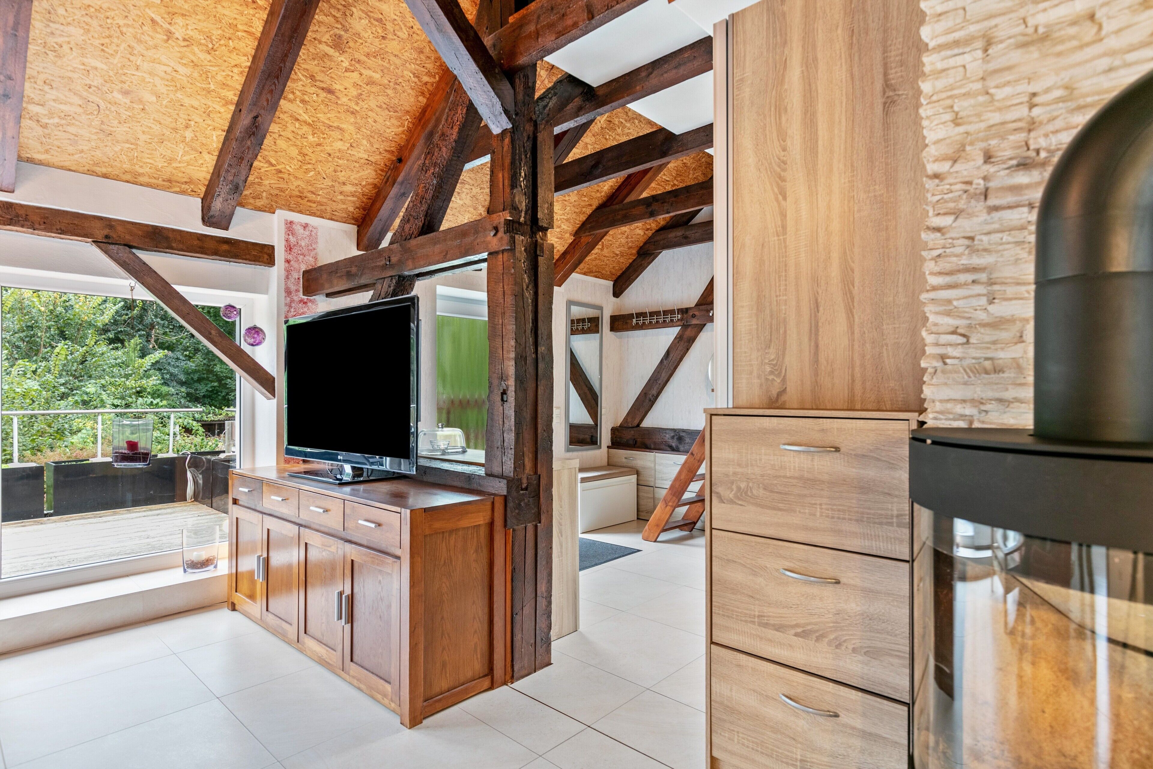 Een moderne keuken met houten balken, een grote televisie en een accentmuur van steen.