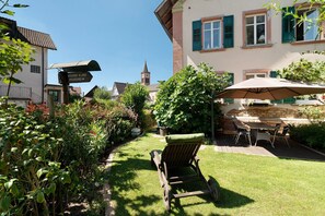 Ein Garten mit Rasen, einem hölzernen Stuhl, einem Tisch mit Stühlen und einem Wegweiser.