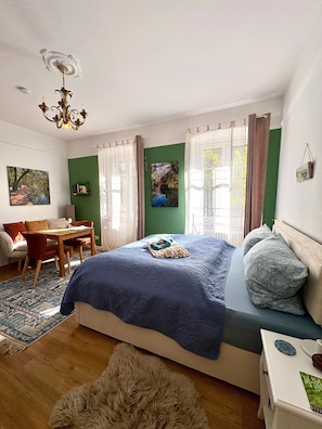 A bedroom with a bed, a desk, a chair, a rug, and a chandelier. - Apartment 'Appartement In Historischem Haus' with Private Terrace, Private Garden and Wi-Fi (Ottersweier)