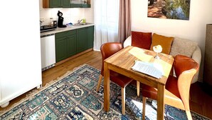 Un espacio habitable compacto con cocina, comedor y un amplio ventanal.