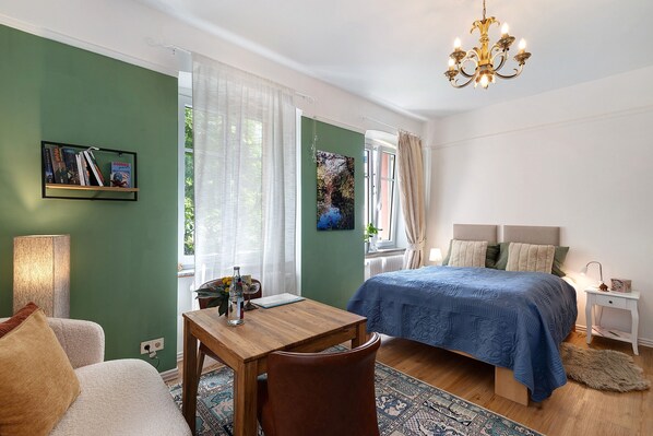 Ein Schlafzimmer mit Bett, Nachttisch, Lampe und Blick ins Freie.