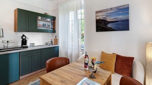 Una cocina moderna con armarios azul turquesa, una mesa de comedor de madera y vista al mar por una ventana.