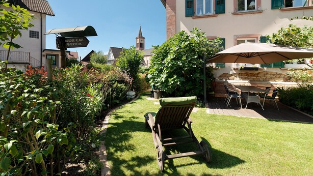 A garden with a lawn, a wooden chair, a table with chairs, and a signpost. - 'Single Room Ahorn, Nature, Wellness' with Private Terrace, Garden, and Wi-Fi (Ottersweier)