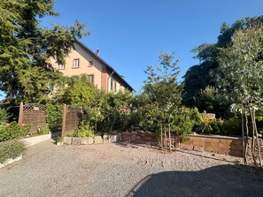 Ein Gebäude mit Kiesweg, umgeben von Bäumen und Sträuchern.