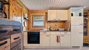 A compact kitchen with wooden cabinetry, a built-in oven, and a window. - Holiday Home 'Häuschen Grau' with Private Garden and Wi-Fi (Scheibenberg)
