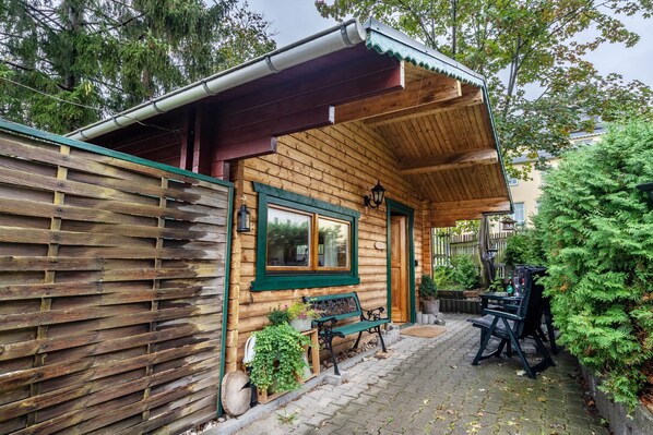 Eine Holzhütte mit Veranda, einer Bank und einem Tisch mit Stühlen.