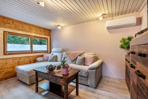 Ein gemütliches Zimmer mit Holzbalkendecke, einer Couch, einem Tisch mit Teekanne und einem Topf mit Pflanze.