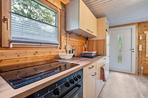 Eine moderne Küche mit Holzschränken, einem eingebauten Herd und einem Fenster mit Jalousien.